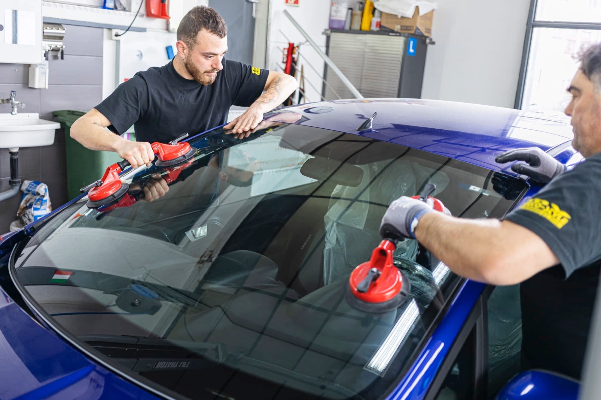 Pose d'un pare-brise à deux techniciens chez MV Auto Style
