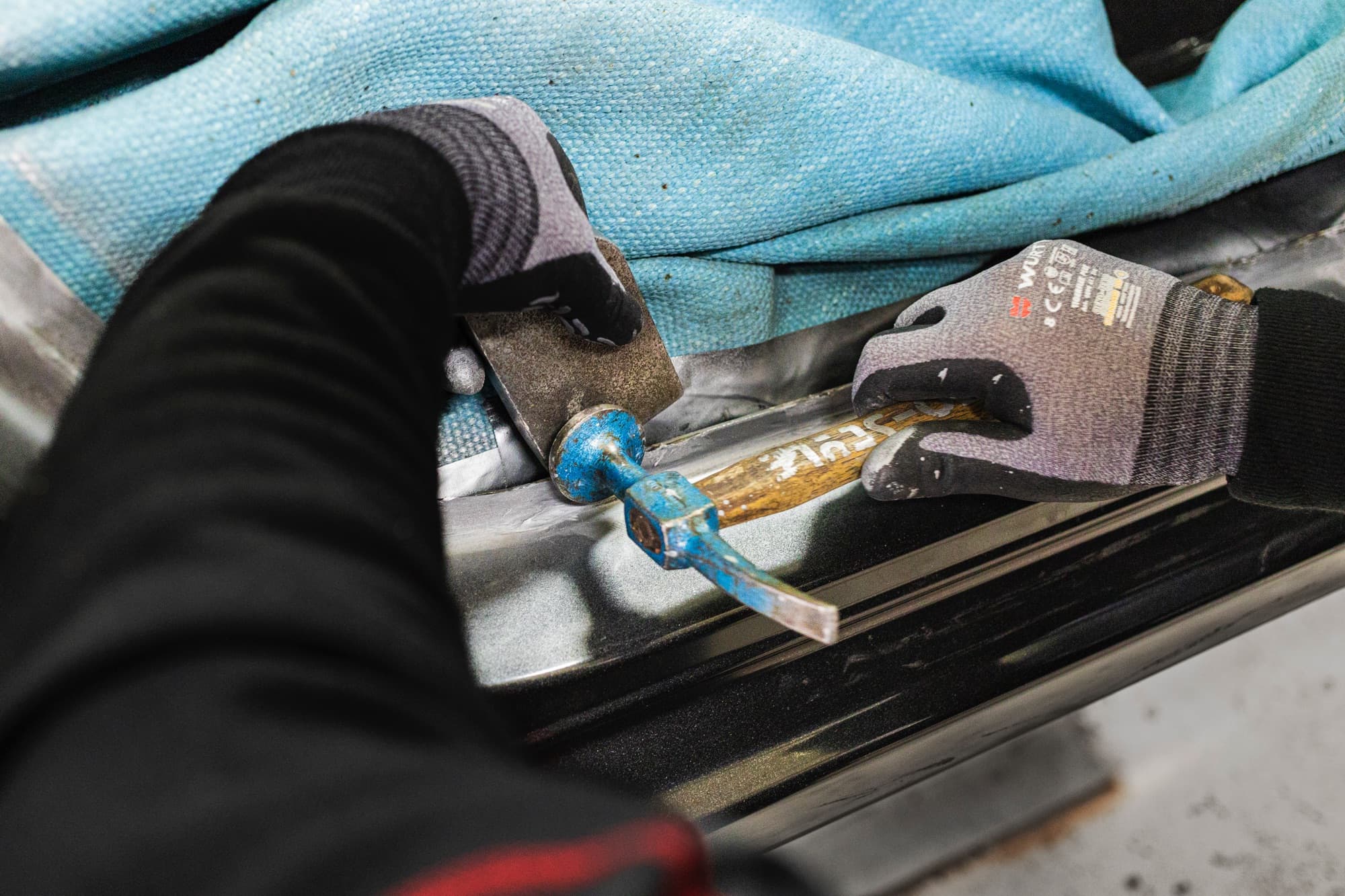 Débosselage au marteau et tas sur un bas de caisse